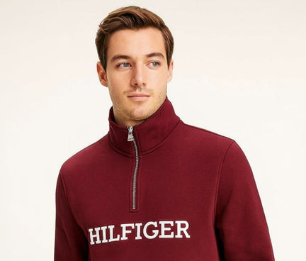 Man wearing a burgundy Tommy Hilfiger sweatshirt on a white background